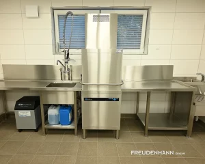 Spülstraße für den Gastronomiebereich mit Meiko UPster H500 Haubenspülmaschine, Vorspültisch mit Brause, Auslauftisch mit Korbbahnprägung sowie Handwaschbecken mit sensorgesteuerter Armatur.